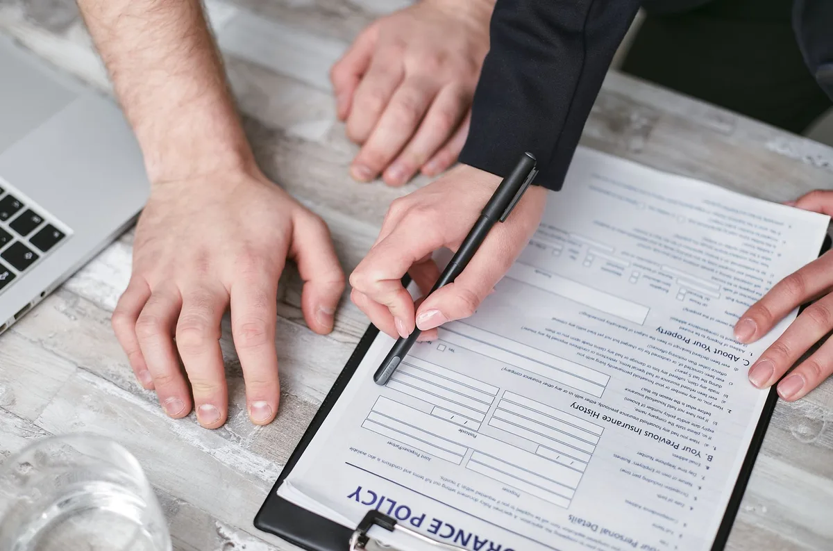 Document d'assurance avec stylo et clauses bénéficiaires à remplir