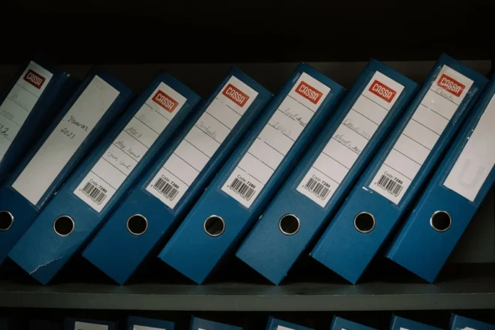 Mains organisant des documents et dossiers sur un bureau avec des notes datées Mains organisant des documents et dossiers sur un bureau avec des notes datées