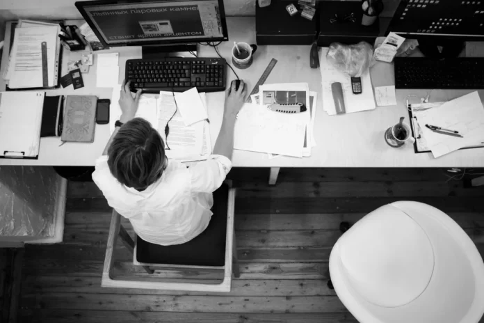 Personne organisant des documents professionnels devant un ordinateur sur un bureau