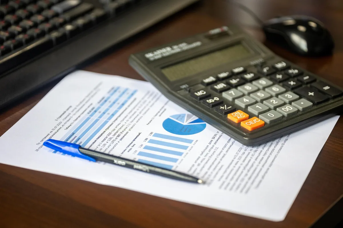 Calcul de revenus avec calculatrice et documents financiers sur un bureau