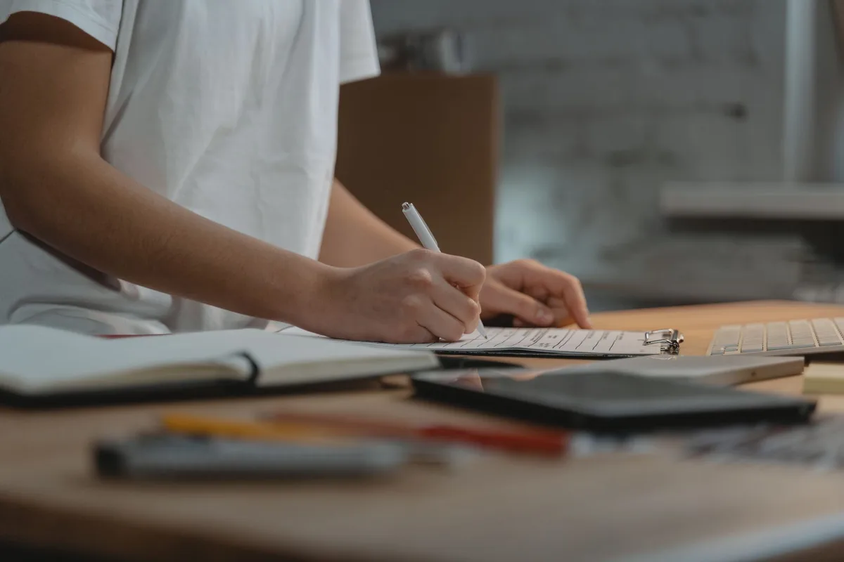Personne analysant des documents et prenant des notes à son bureau