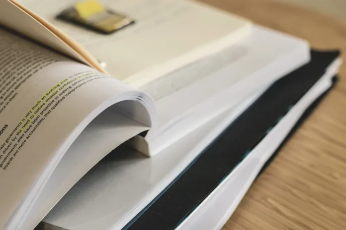 Mains feuilletant des documents de carrière et un dictionnaire sur un bureau d'étude Mains feuilletant des documents de carrière et un dictionnaire sur un bureau d'étude