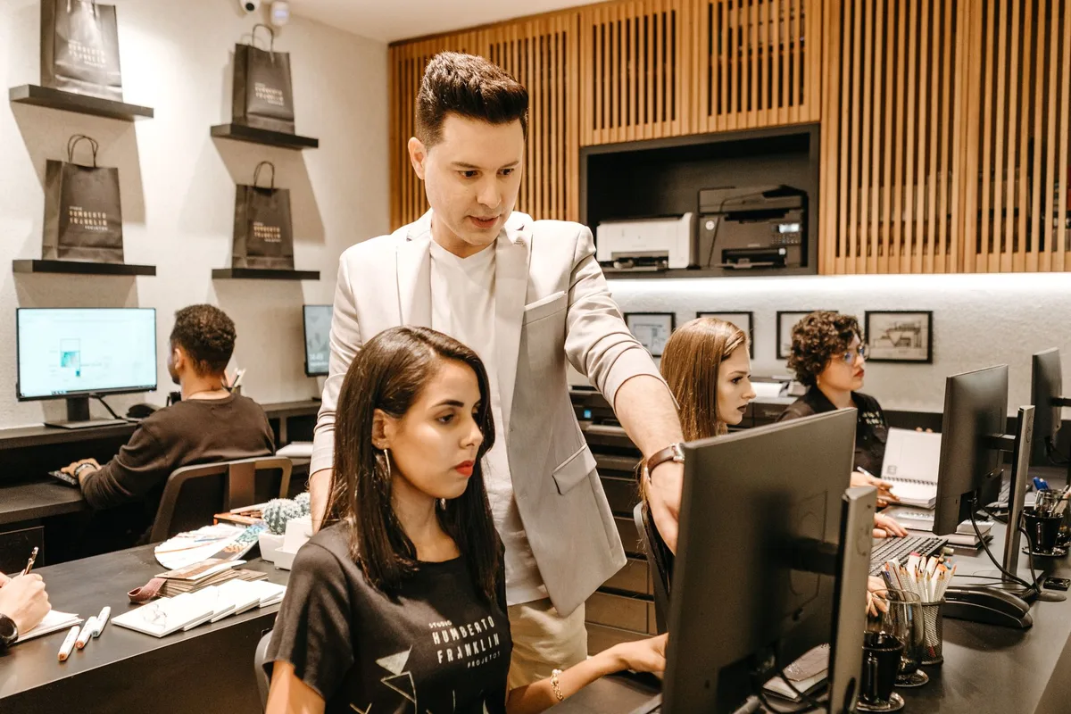 Un mentor encadre un collaborateur lors d'une tâche pratique en entreprise.