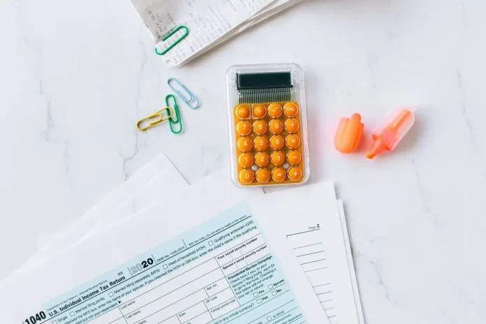 Documents fiscaux et formulaires d'impôt sur un bureau professionnel avec calculatrice Documents fiscaux et formulaires d'impôt sur un bureau professionnel avec calculatrice