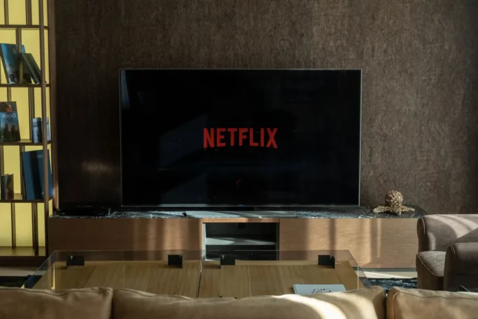Personne regardant un écran de télévision avec menu de streaming dans un salon Personne regardant un écran de télévision avec menu de streaming dans un salon