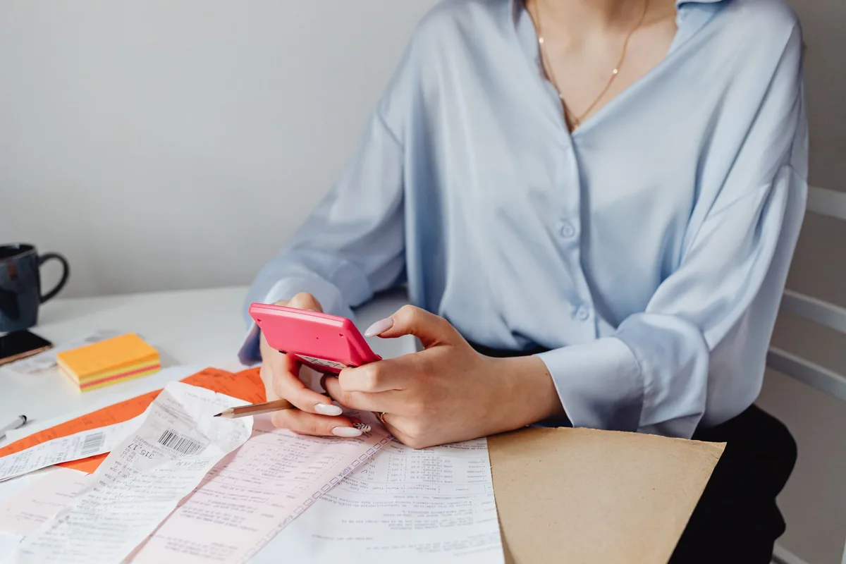 Une personne calcule l'impact financier d'une réduction d'allocations sur un document.