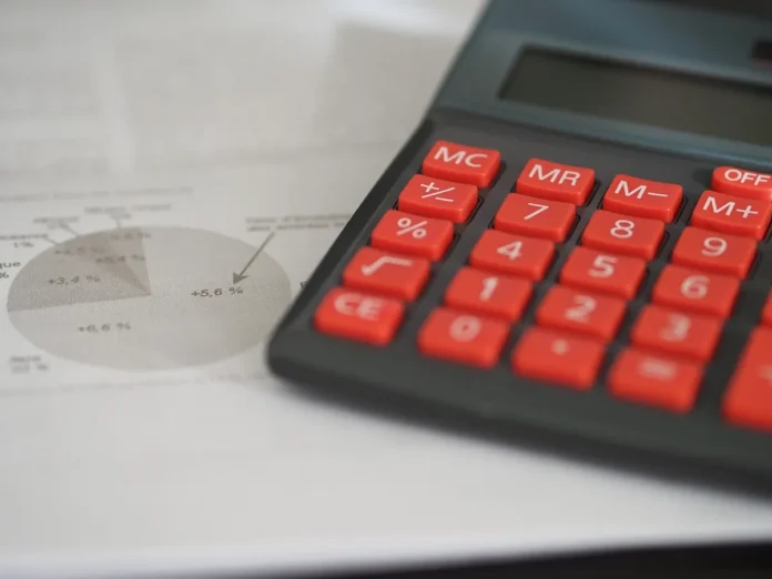 Mains tenant des documents immobiliers et fiscaux sur un bureau avec globe et calculatrice