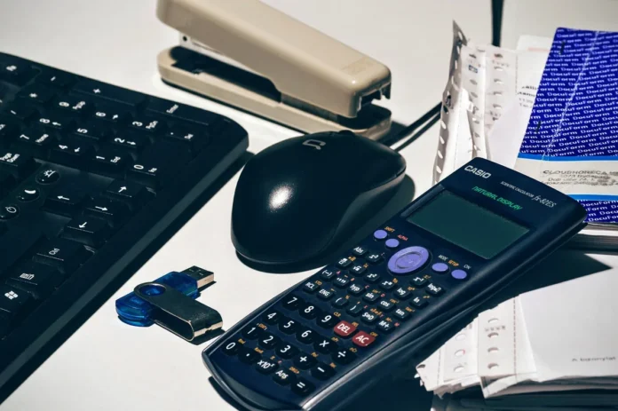 Mains anonymes autour d'une table de réunion avec documents financiers et calculatrice, en plein jour Mains anonymes autour d'une table de réunion avec documents financiers et calculatrice, en plein jour