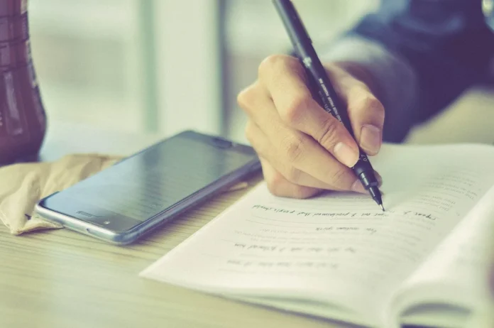 Mains examinant des documents et dossiers sur un bureau de travail, avec bloc-notes et enregistreur Mains examinant des documents et dossiers sur un bureau de travail, avec bloc-notes et enregistreur