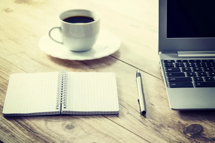 Table de coworking en journée avec ordinateur, formulaires et tasses de café, vue sur la ville