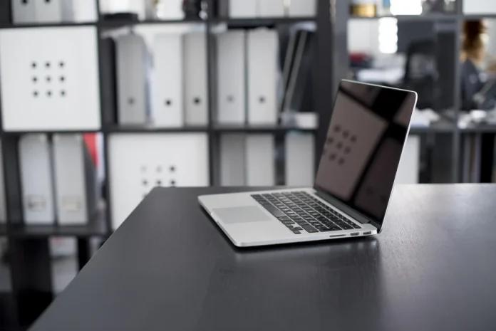 Consultant informatique pointant un diagramme d'architecture sur un écran d'ordinateur portable au bureau
