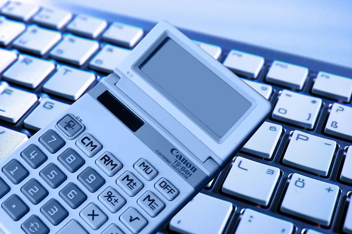 Calculatrice et factures sur un bureau pour estimer coûts sur 12 mois