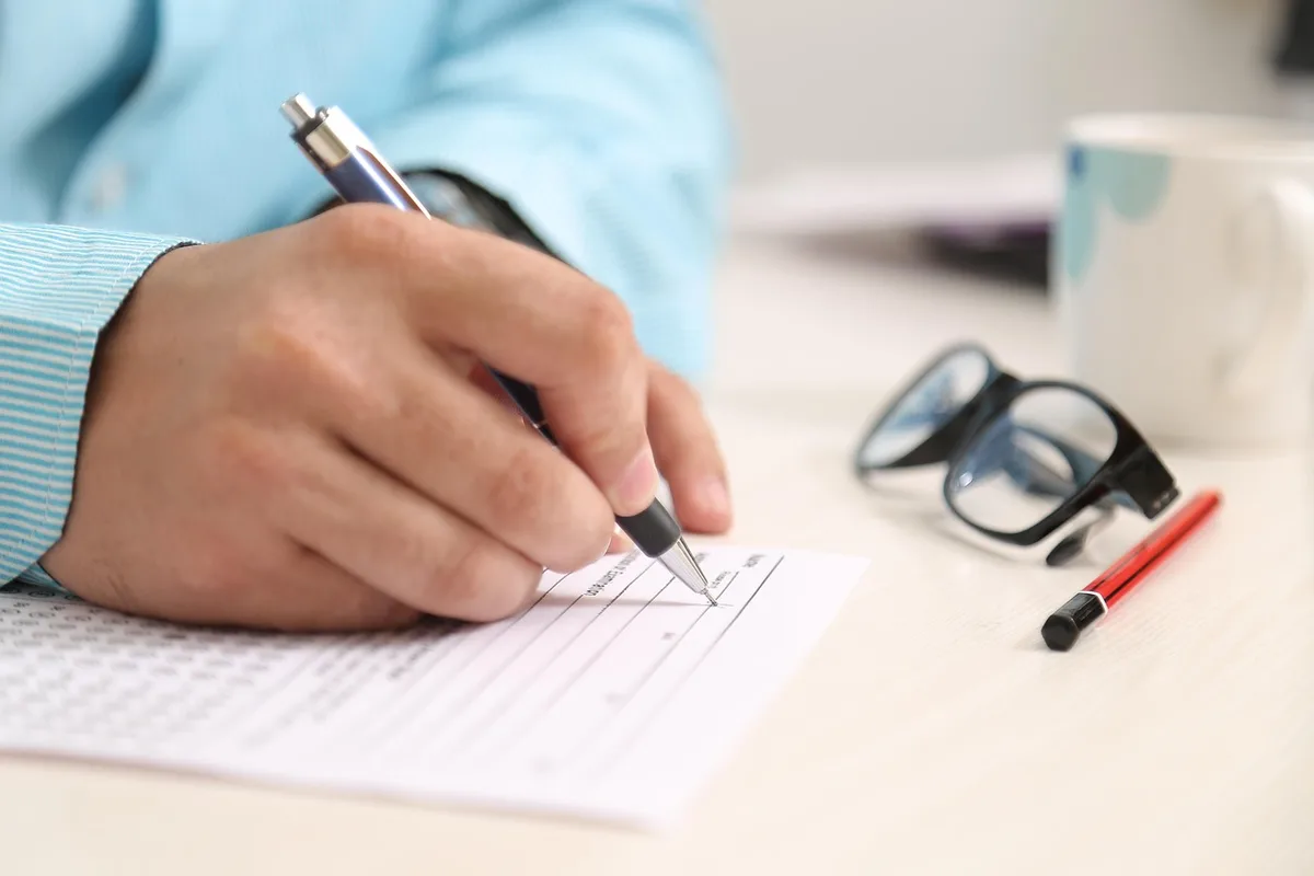 Personne remplissant un chèque avec les informations obligatoires