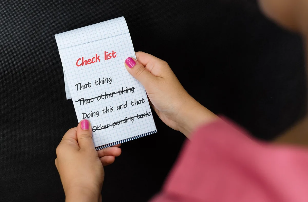 Main tenant un trousseau de clés et une checklist de nettoyage lors d'un état des lieux