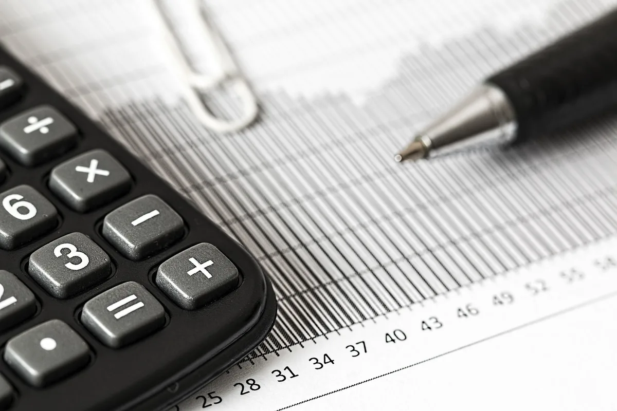 Locataire calculant une réduction de loyer avec papiers et calculatrice sur une table