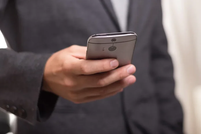 Mains tenant un smartphone pliable ouvert sur une table de café en plein jour Mains tenant un smartphone pliable ouvert sur une table de café en plein jour