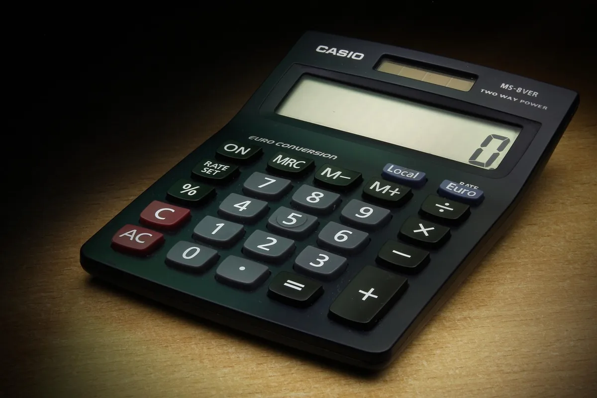 Calculatrice et reçus sur un bureau pour illustrer les frais de transaction