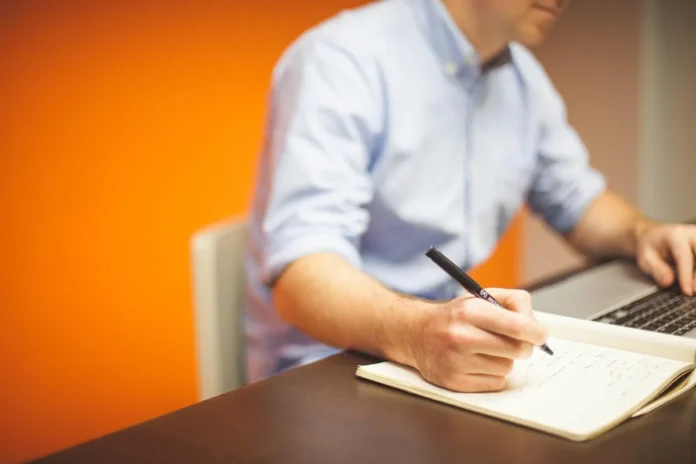 Bureau lumineux avec ordinateur portable, papiers et mains en action, symbolisant la création d'entreprise