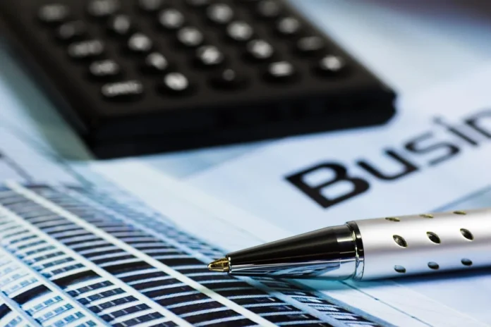 Mains triant des documents financiers près d'une calculatrice sur une table ensoleillée Mains triant des documents financiers près d'une calculatrice sur une table ensoleillée