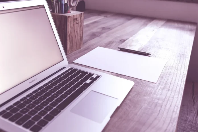 Personne anonyme tapant sur un clavier près d'un carnet, lumière du jour Personne anonyme tapant sur un clavier près d'un carnet, lumière du jour