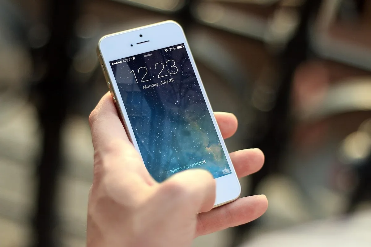 Smartphone montrant une notification de virement bancaire sur une table ensoleillée
