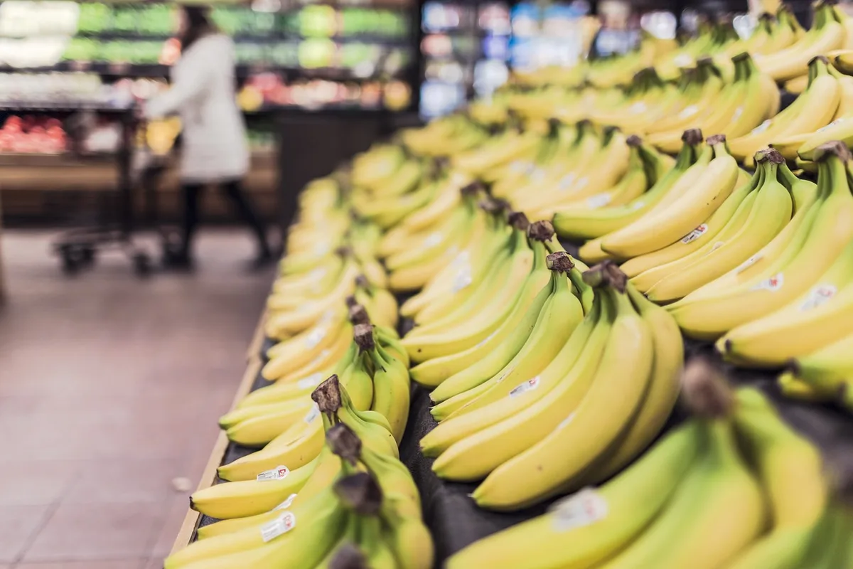 Employé de supermarché manipulant caisses de denrées près d'une réserve
